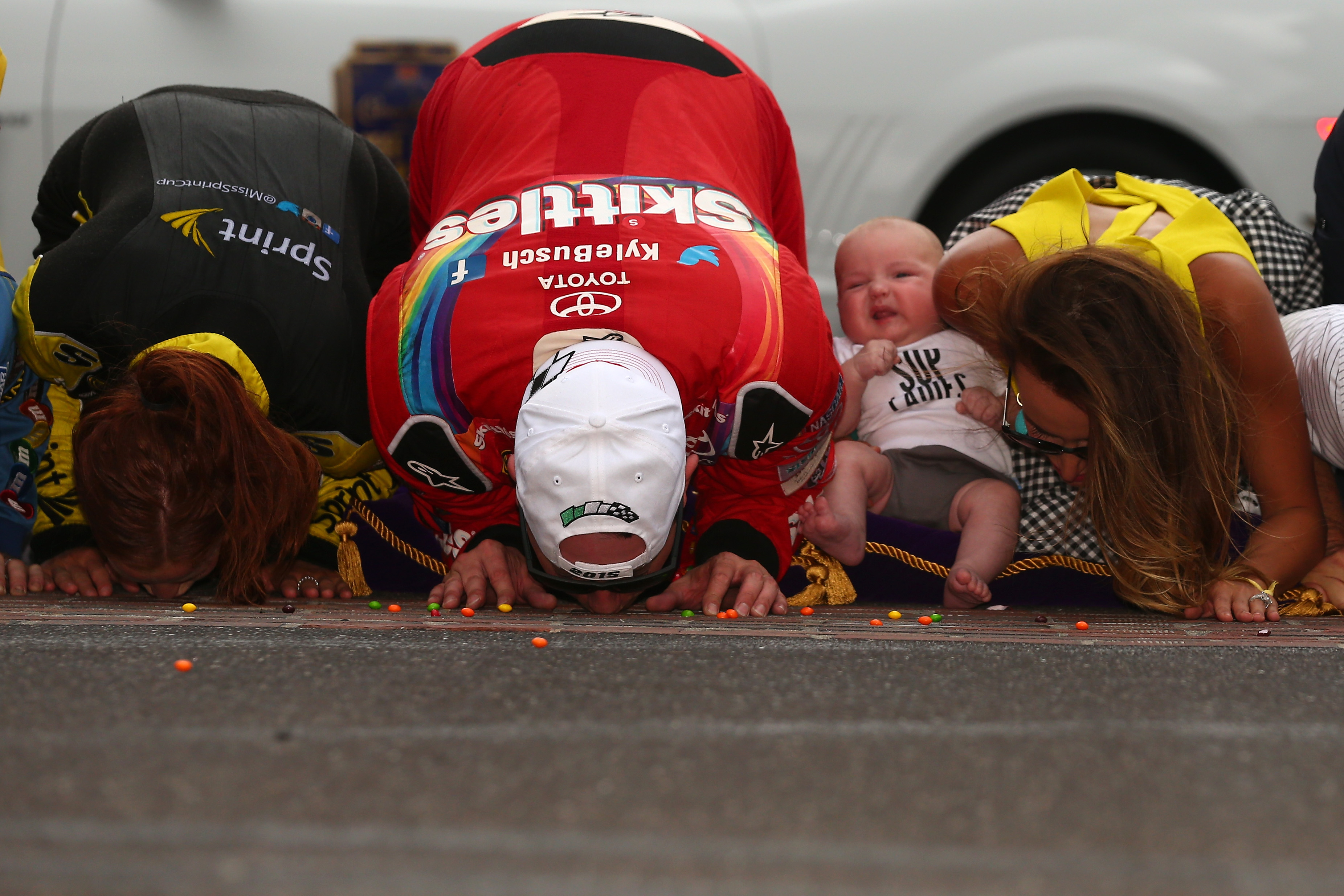 Kyle Busch kisses the bricks with his family at Indianapolis, 2015.