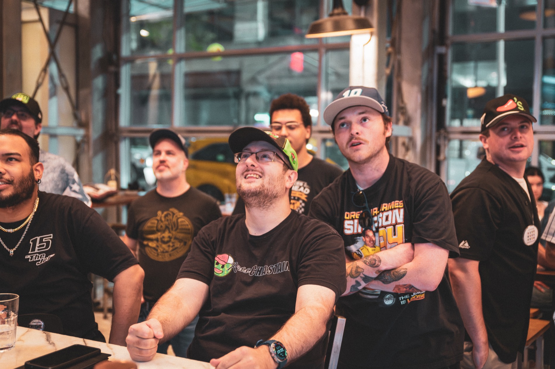 NASCAR fans in driver shirts and caps watch the race on a screen at Burgerology Midtown in New York.