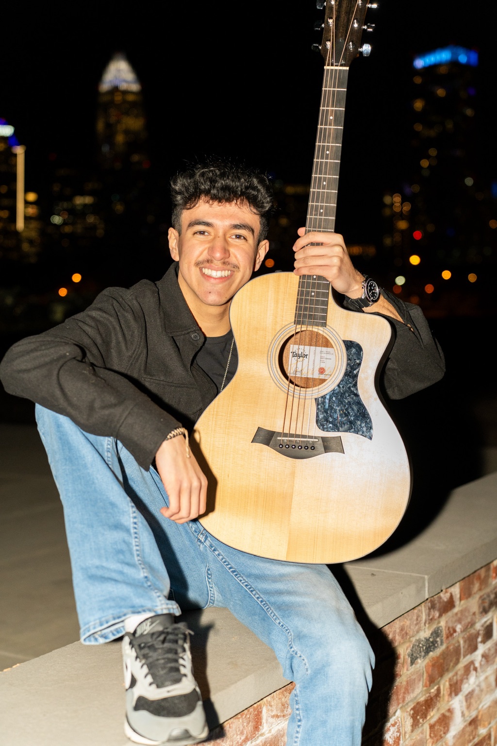 Anthony Vasquez seated with an acoustic guitar