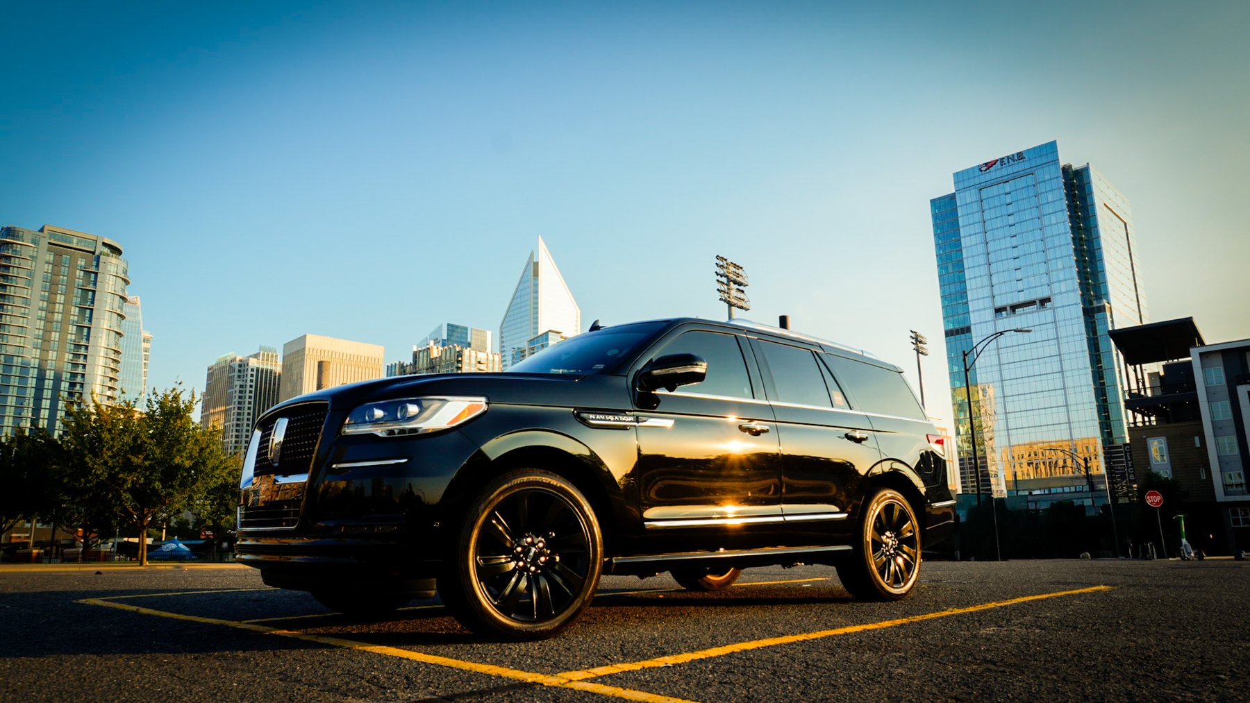 Black SUV parked at sunset beside a glass office tower in uptown Charlotte