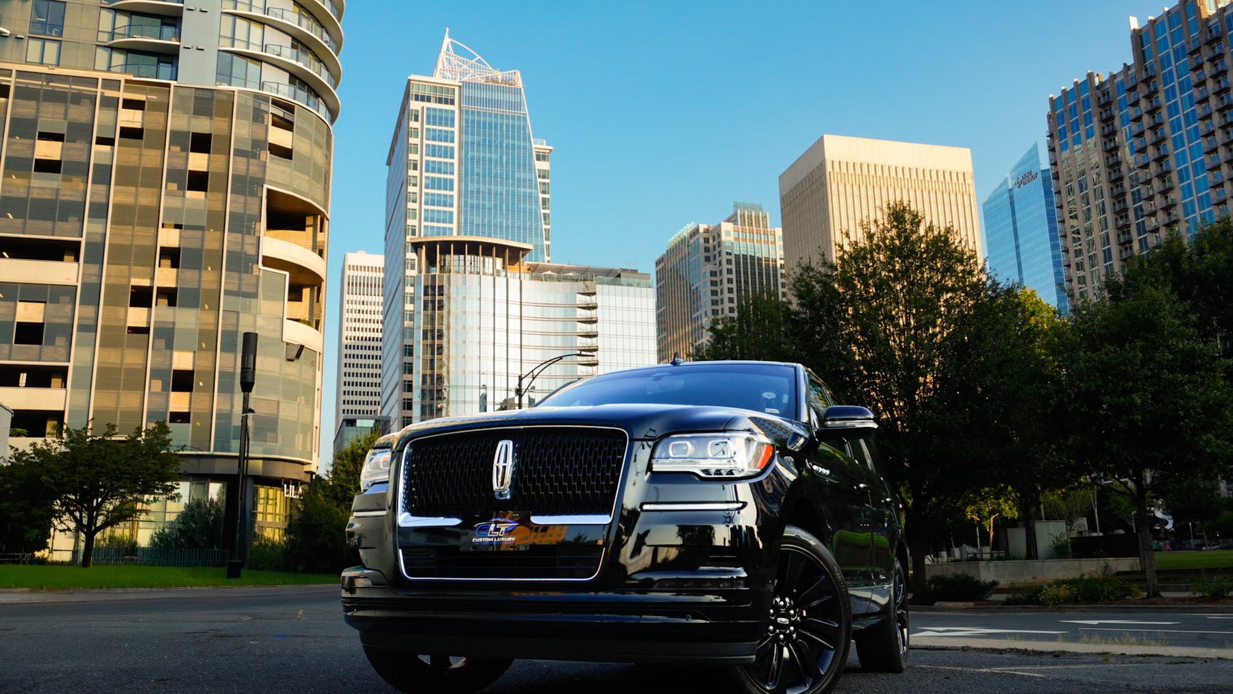 Black SUV parked on a street below uptown Charlotte towers