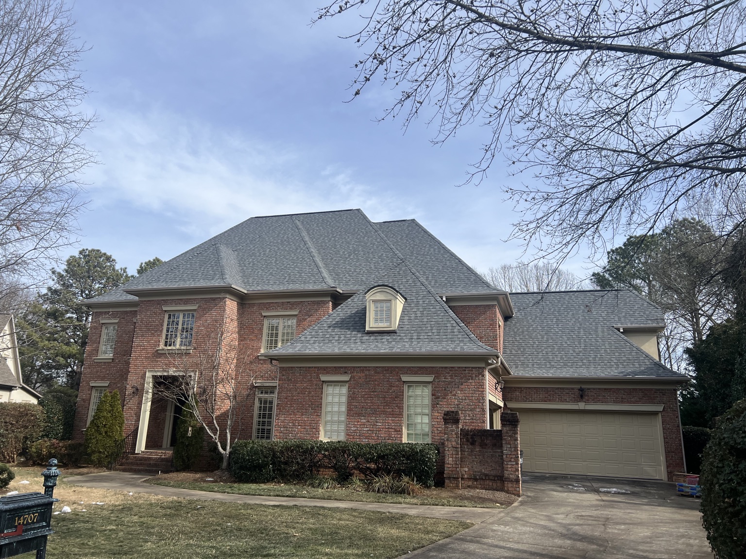 Slate-gray shingle roof on a two-story brick home with a dormer and attached garage