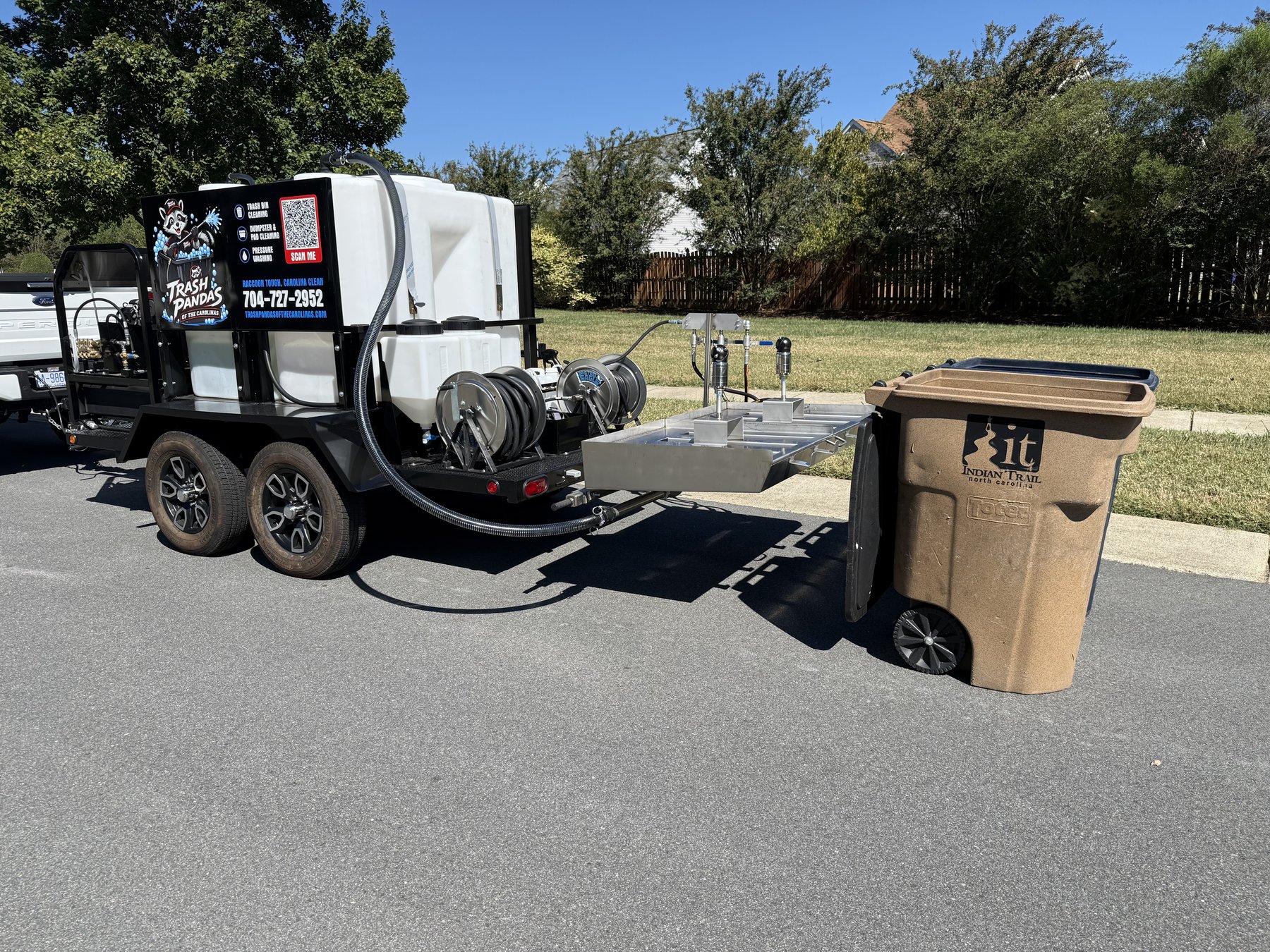 Trash can on the cleaning lift of the Trash Pandas trailer at a curb